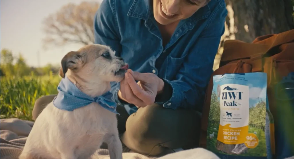 Woman feeding dog a treat outside